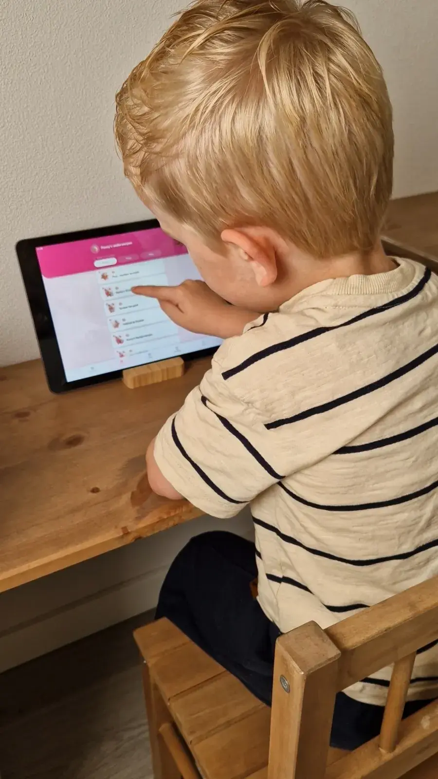 Een kind speelt thuis aan tafel een missie van Penny op de tablet